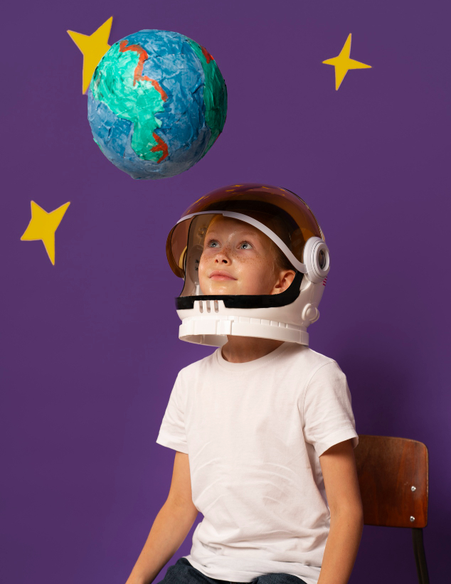 Boy with an astronaut helmet looking at a model of the earth